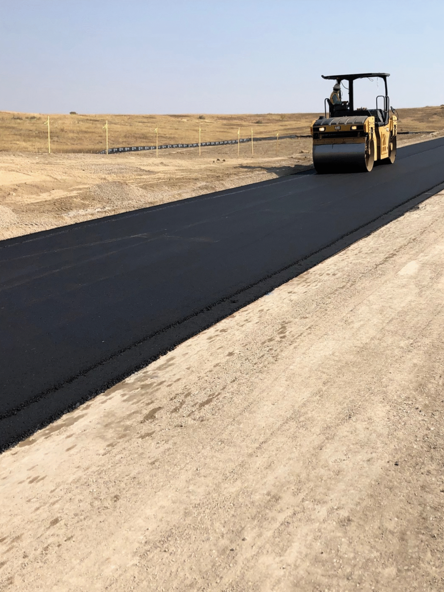 HEI Team member utilizing a Caterpillar Compactor on asphalt road