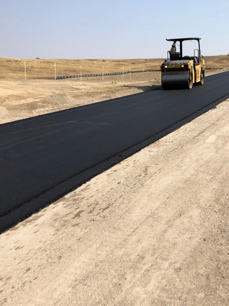 HEI Team member utilizing a Caterpillar Compactor on asphalt road