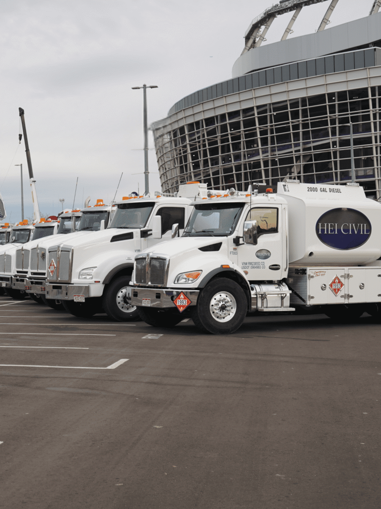 HEI CO Equipment Team's Fleet of Trucks Lined Up outside a stadium